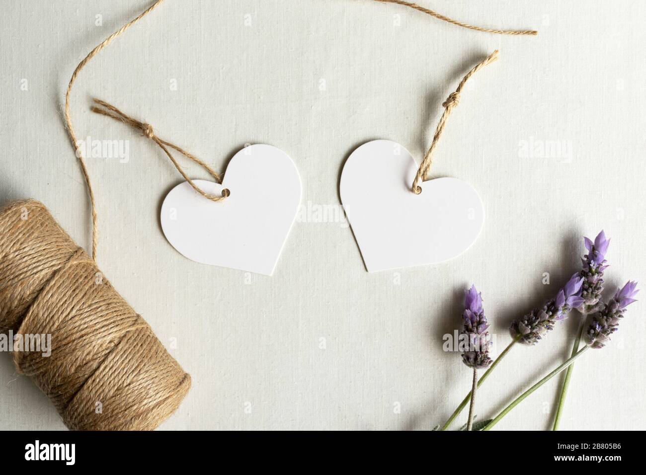 Herzförmige Geschenkanhänger - zwei weiße Herzanhänger mit Lavendel und Garn zum Geburtstag der Hochzeit Stockfoto