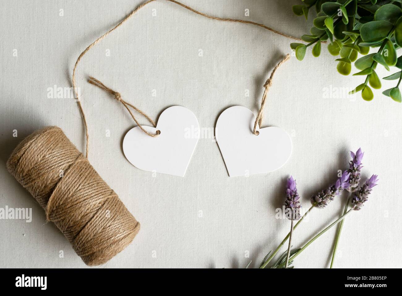 Zwei herzförmige Geschenkanhänger verspotzen - zwei weiße Herzanhänger mit Lavendel und Garn zum Geburtstag der Hochzeit Stockfoto