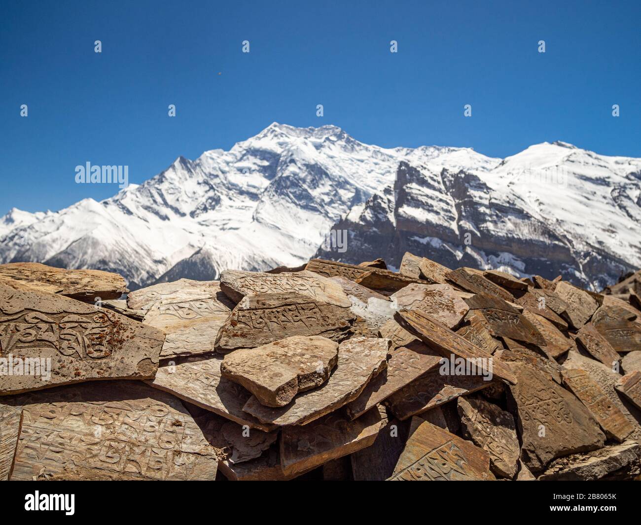 Buddhistische Zeichen, die in Steinen mit Gebirgszug im Hintergrund im Gebiet Nepal-Himalaya Annapurna gehauen wurden Stockfoto Buddhistische Zeichen, die in Steinen mit Gebirgszug im Hintergrund im Gebiet Nepal-Himalaya Annapurna gehauen wurden Stockfoto