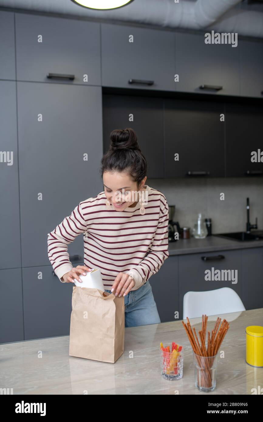 Junge Frau packt Mittagskasten in der Küche aus Stockfoto