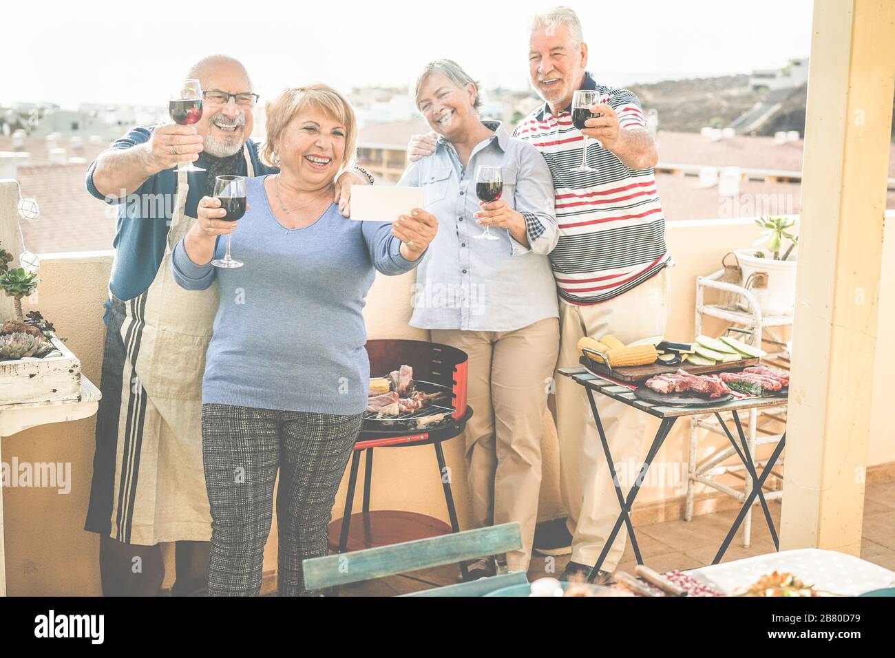 Fröhliche Senioren Freunde machen ein selfie-foto mit Smartphone beim Barbecue-Dinner im Terrassenhaus - reife Leute, die Spaß haben und Wein trinken - konzentrieren sich auf Stockfoto