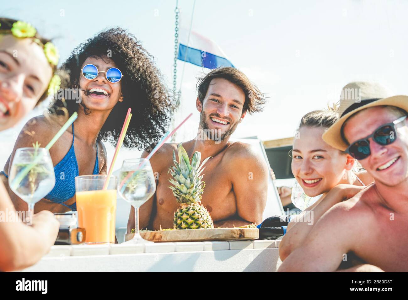 Gruppe glücklicher Freunde, die auf der Bootsparty tropische Cocktails trinken - junge Leute haben Spaß auf der karibischen Seereise, die Ananas essen und lachen - Jugend Stockfoto