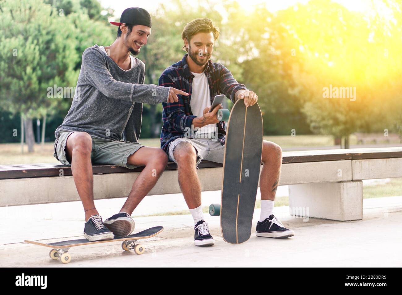 Junge Skater haben Spaß mit Smartphone mit Hintergrundbeleuchtung - beste Freunde teilen Freizeit mit neuer Trendtechnologie - Technology Suchtkonzept Stockfoto