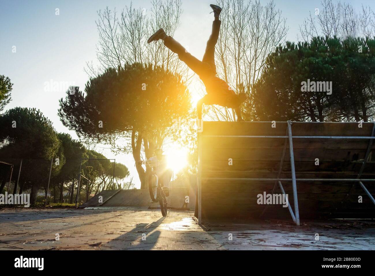 Freunde, die gleichzeitig Freestyle-Biking und Breakdancing durchführen - Break Dancer und Biker trainieren im Stadtpark - Extreme Sportkonzept - Stockfoto