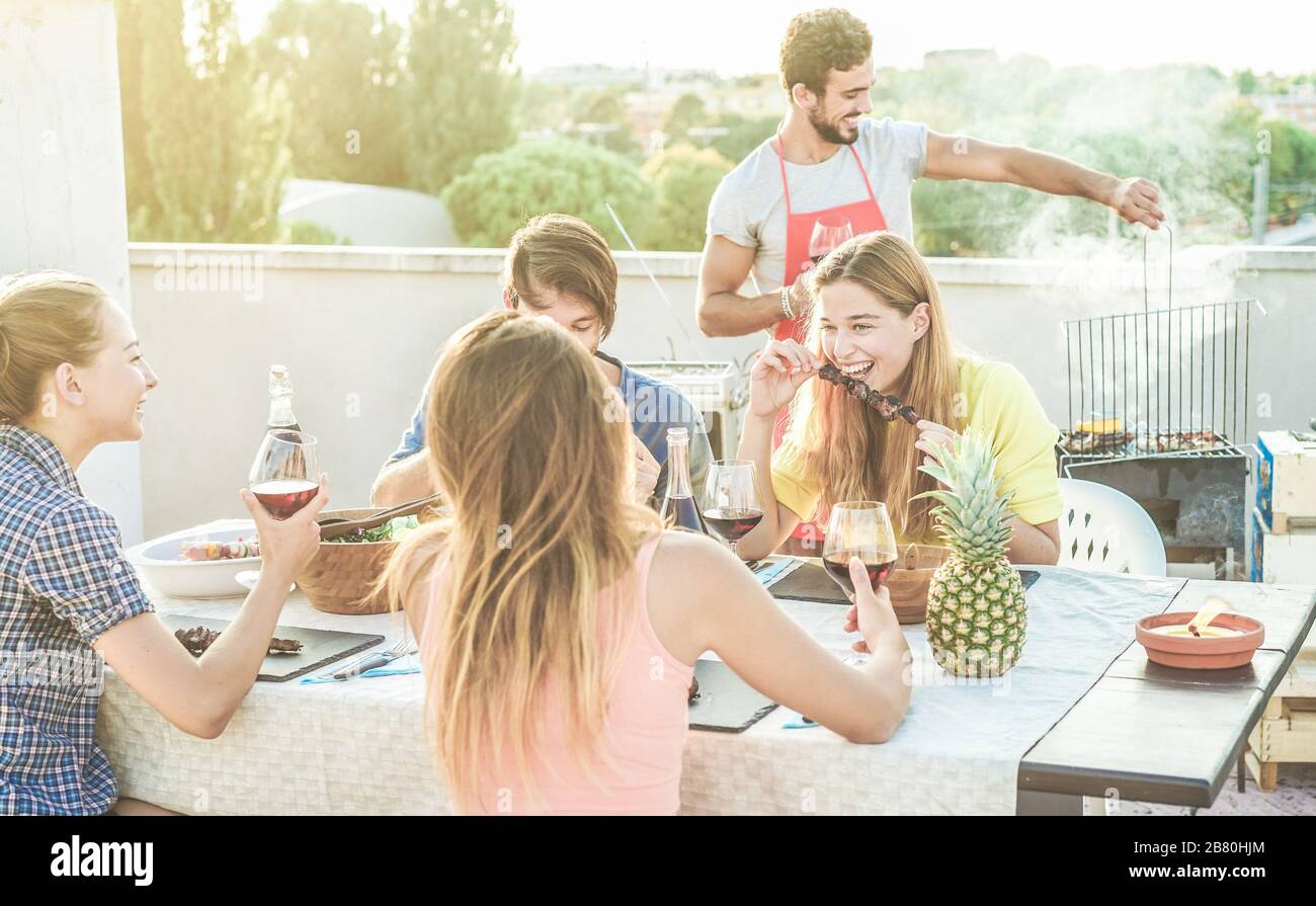 Junge Freunde, die Rotwein auf der Grillparty auf dem Dach essen und trinken - fröhliche Leute grillen und Spaß beim grillabendessen im Freien haben - Hauptaugenmerk auf Righ Stockfoto