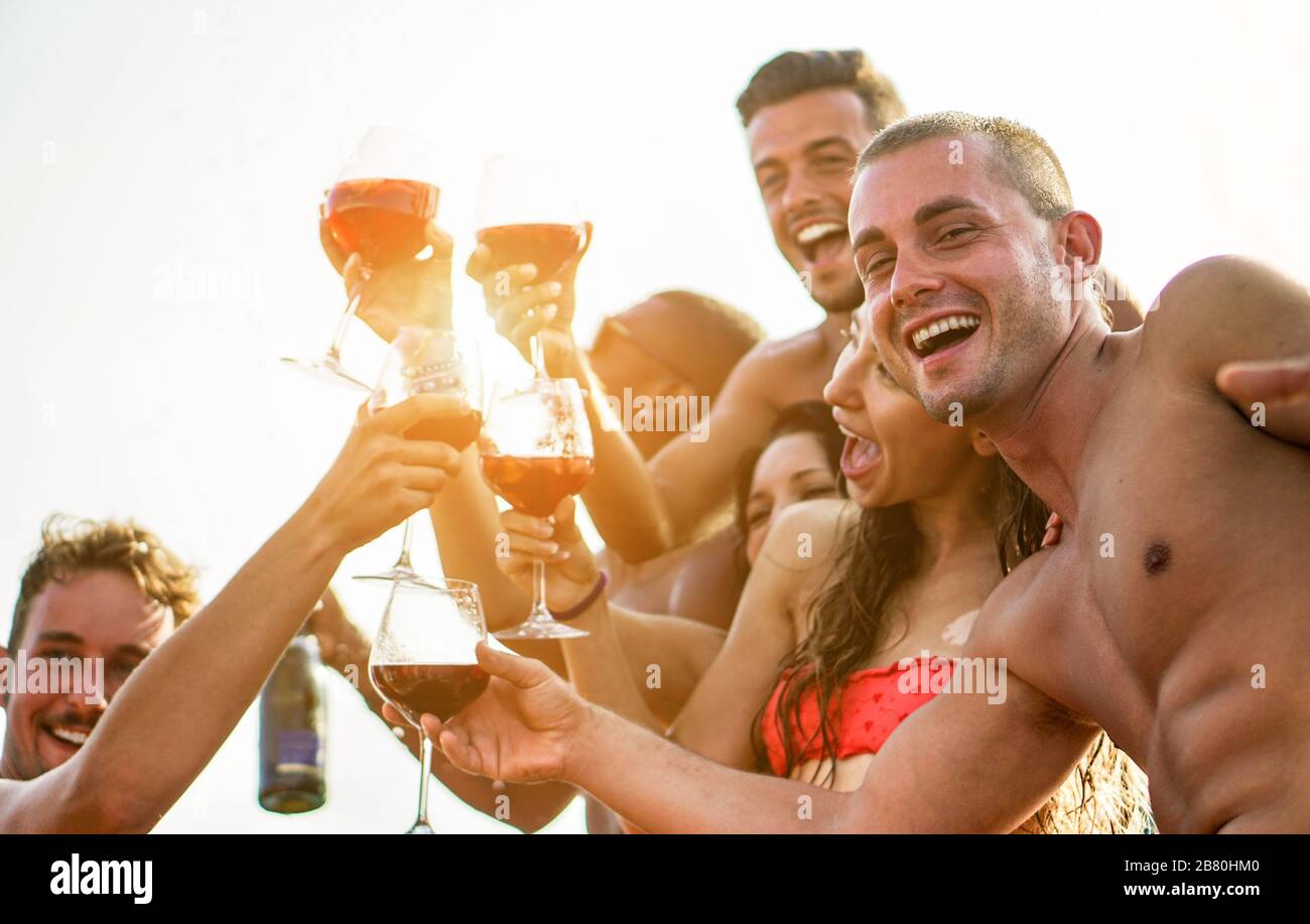 Fröhliche Freunde haben lustige Momente im Sommerurlaub im Freien - junge Leute jubeln mit Rotweinsangria bei Partyuntergang am Strand - Friendshi Stockfoto