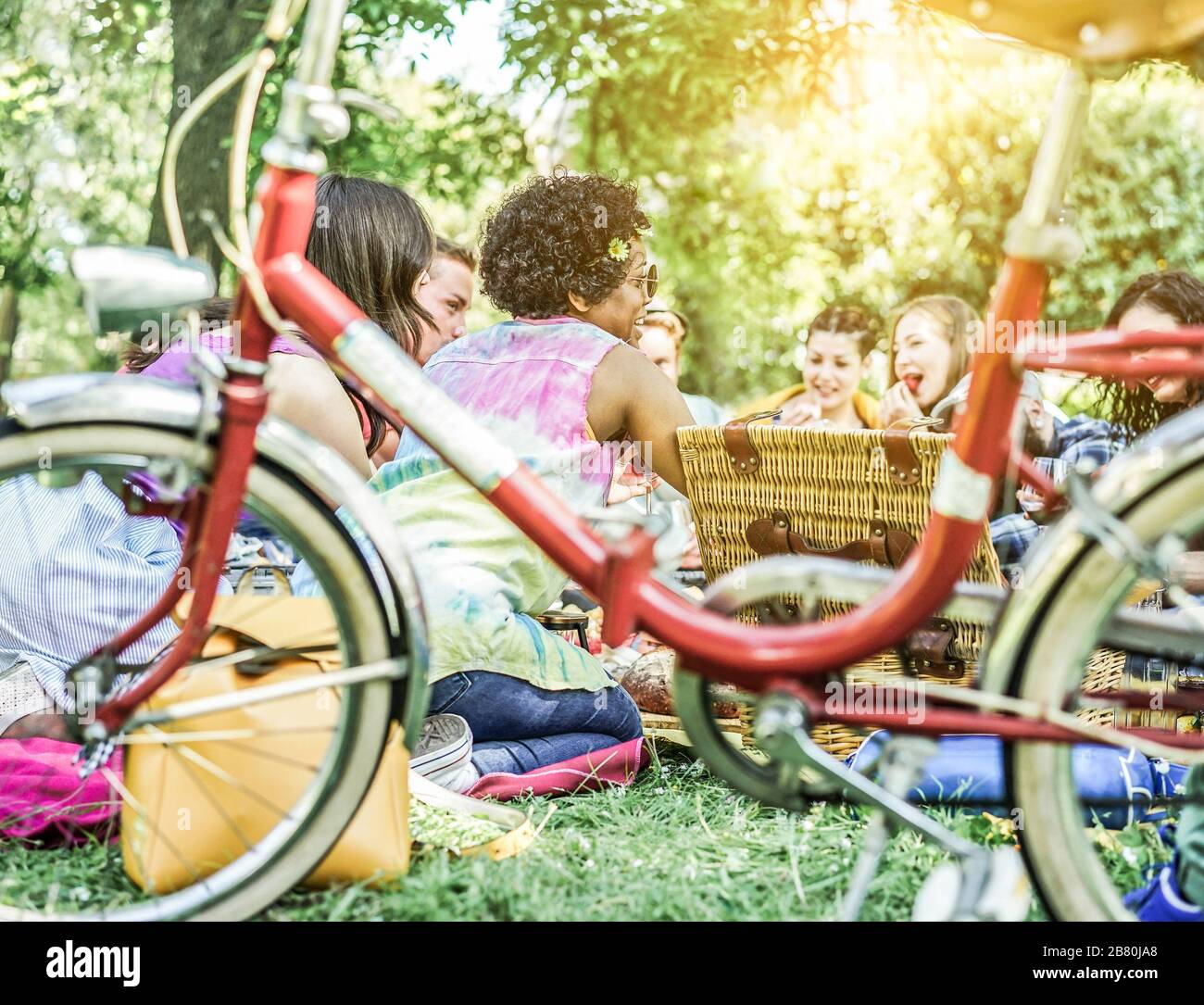 Diverse Kulturfreunde machen Picknick im Stadtpark im Freien - junge Trendsleute essen Abendessen im Hinterhof draußen - Fokus auf afrikanisches Haarmädchen - out Stockfoto