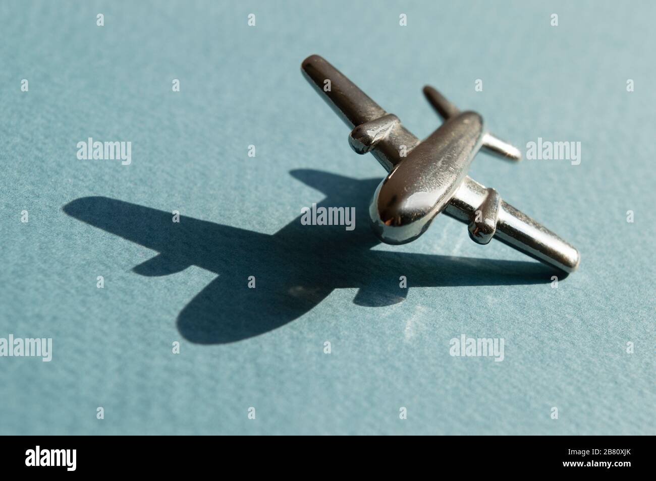 Metallfigur des kleinen Flugzeugs auf dem Turqouise- und hellblauen Geometriehintergrund. Konzeptionelles Trendfoto von Flugzeugen. Luftfahrtindustrie Stockfoto