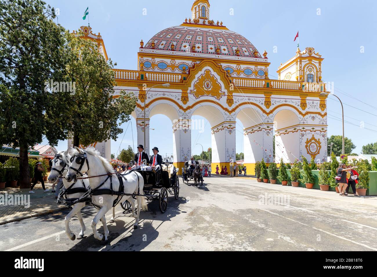 Pferdekutschen und Eingangsbogen (Portada) im Hintergrund auf der Aprilmesse (Feria de Abril), Messe Sevilla Stockfoto