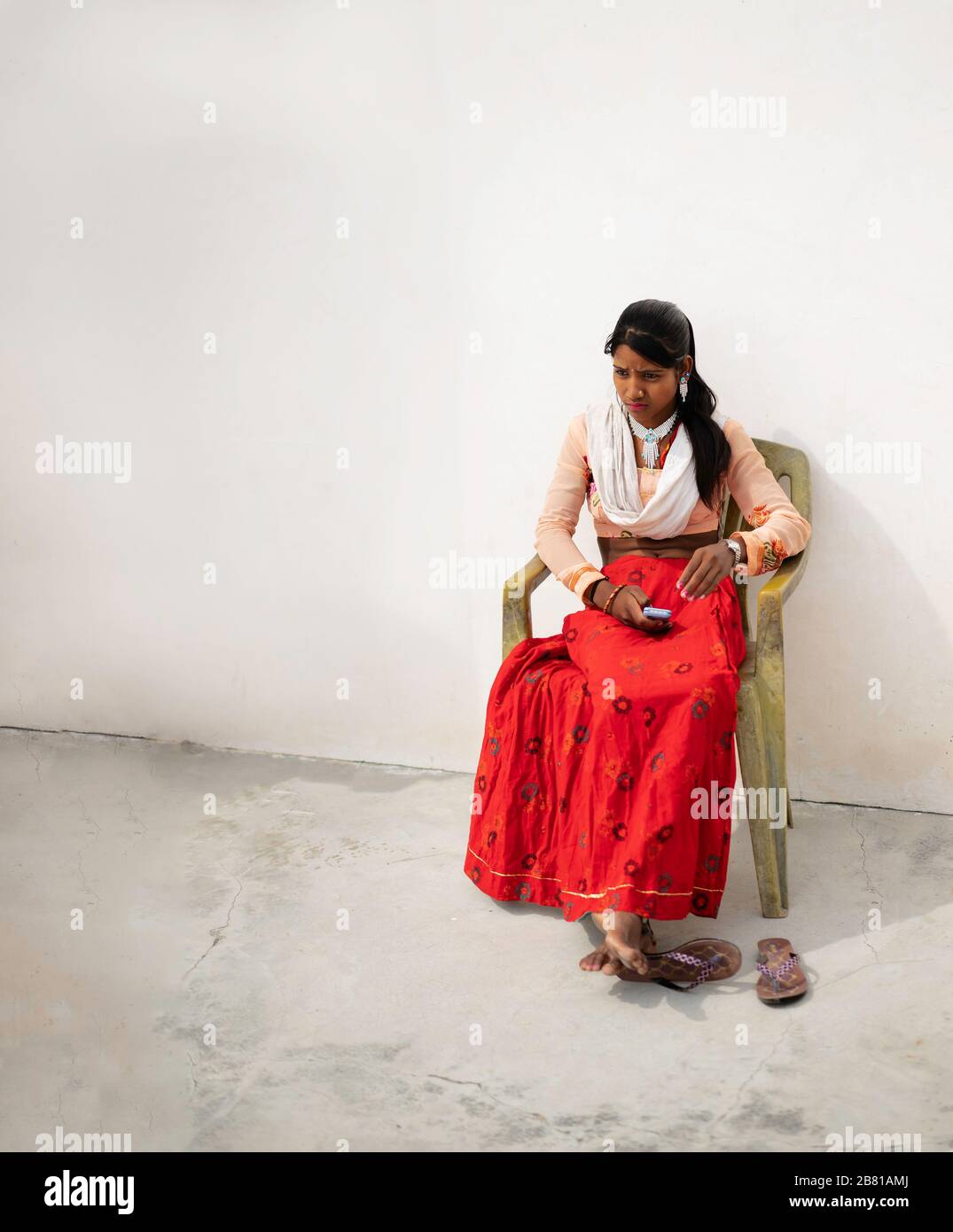Junge Indianerin in bunter Kleidung, die am 26. Oktober 2019 in U auf dem Stuhl mit Handy und nachdenklicher Ausdrucksweise sitzt Stockfoto