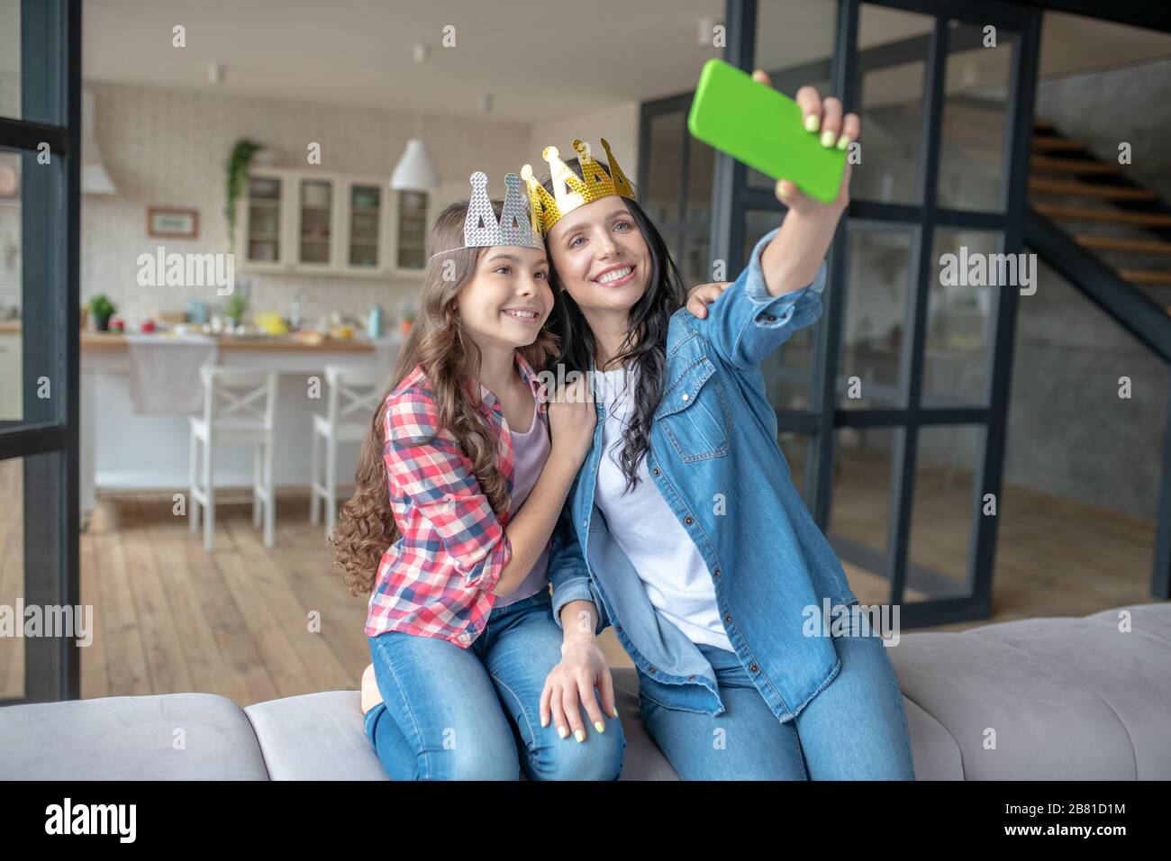 Mutter und Tochter tragen Kronen und machen Fotos Stockfoto