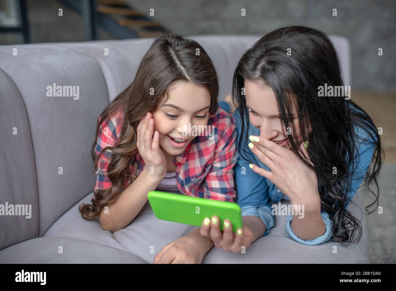 Mutter und Tochter legen sich auf das Sofa und schauen durch die Fotos Stockfoto