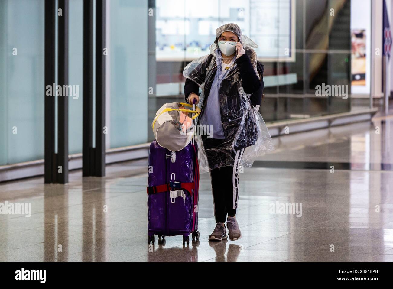 Ein maskierter Passagier, der eine Duschkappe und eine Gesichtsmaske als protektive Maßnahme gegen das Covid19 Coronavirus trägt, als er am internationalen Flughafen von Hongkong ankommt. Während sich der Ausbruch des Coronavirus weltweit verschlimmert, fliegen Hunderte von Passagieren und Studenten zurück nach Hongkong. Passagiere waren maskiert und mehrere Personen bedeckten sich in einer schützenden Verkleidung von Kopf bis Fuß. Stockfoto