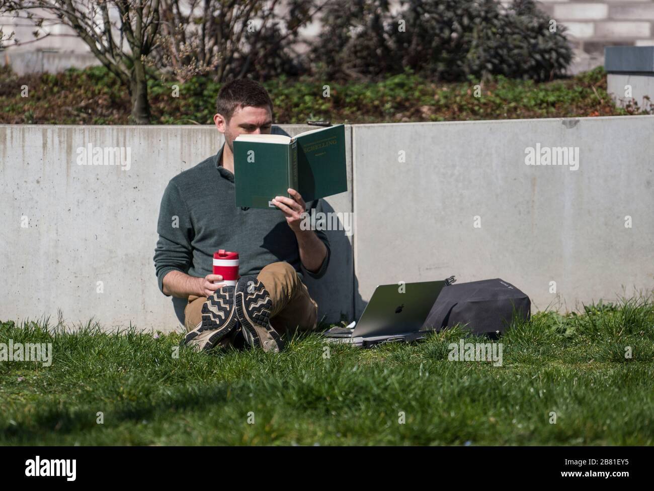 19. März 2020, Hessen, Frankfurt am Main: Ein Doktorand der deutschen Studien an der Frankfurter Goethe-Universität liest zur Vorbereitung seiner Doktorarbeit eine Schiller-Arbeit im Sonnenschein. Foto: Frank Rumpenhorst / dpa Stockfoto