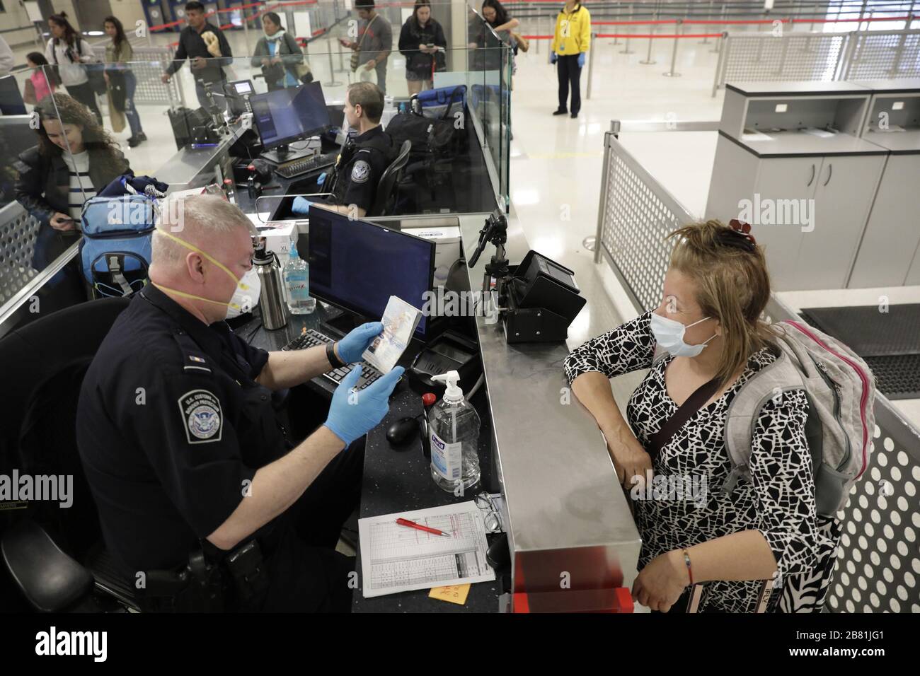 Dulles, Vereinigte Staaten. März 2020. Beamte des US-amerikanischen Zoll- und Grenzschutzamtes für Feldeinsätze sehen internationale Passagiere aus, die am 13. März 2020 auf dem Dulles International Airport in Dulles, Virginia, ankommen. Als Reaktion auf die Coronavirus-Pandemie (COVID-19) haben CBP-Beamte begonnen, persönliche Schutzausrüstung (PSA) zu tragen, während sie mit Passagieren interagieren, die aus dem Ausland ankommen. Viele Passagiere haben auch PSA gespendet, um sich und andere auf ihren Reisen zu schützen. Foto von Glenn Fawcett/U.S. Zoll- und Grenzschutz/UPI-Kredit: UPI/Alamy Live News Stockfoto