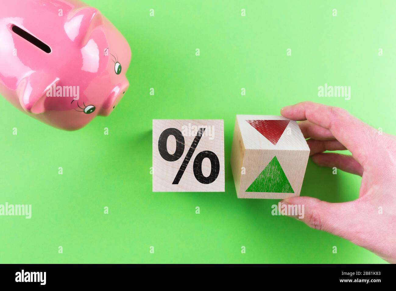 Änderungen des Zinsfinanzkonzepts, Draufsicht des Prozentzeichens und Pfeilsymbols auf Holzwürfeln neben der Schweinebank Stockfoto