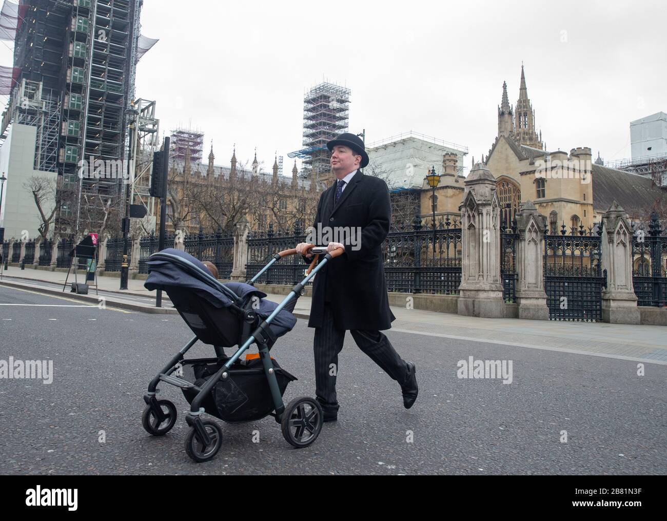 Ein Mann, der einen Bowler-Hut trägt, läuft am Parlament vorbei, da die Straßen Londons aus Angst vor dem Coronavirus verlassen sind. Stockfoto
