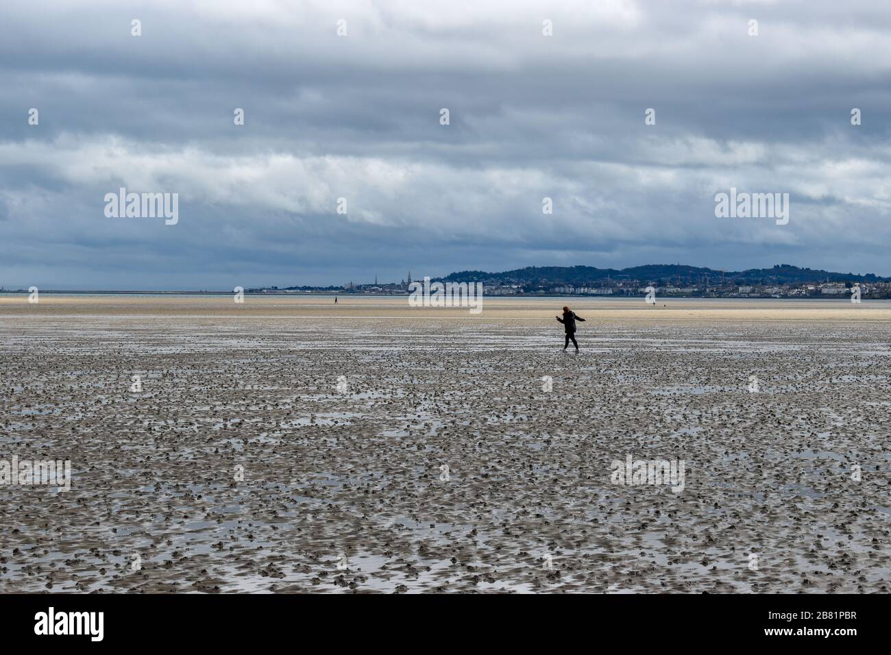 Eine Frau, die soziale Distanzierung aufrecht erhält, die draußen am Strand in Dublin, Irland, spazieren geht Stockfoto