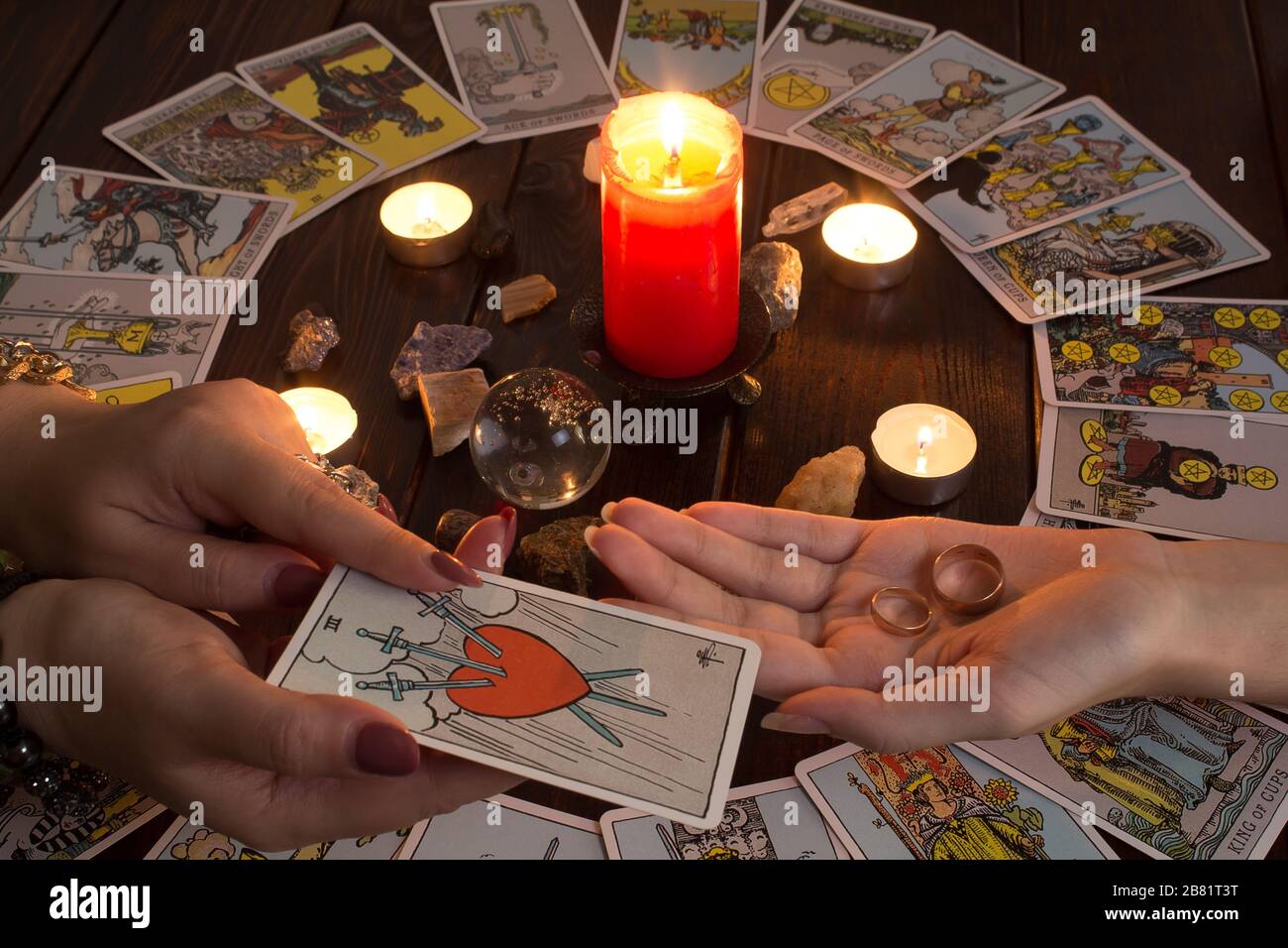 Bangkok, Thailand, März.15.20.das Mädchen hält Trauringe auf der Hand mit Tarot-Karten, Kristallen, einem Zauberball und einer beleuchteten Kerze.Fortune, die für erzählt Stockfoto