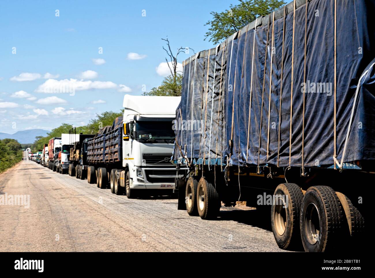 Eine Reihe von Lastwagen steht bewegungslos und erstreckt sich kilometerweit zurück, während die Fahrer darauf warten, den Grenzposten in Chirundu von Simbabwe nach Sambia zu überqueren Stockfoto