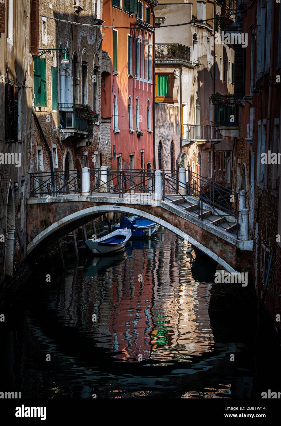 Leere Straßen Venedigs Italien mit einer im Wasser reflektierenden Frau und den traditionellen Häusern und Booten in den Kanälen Stockfoto