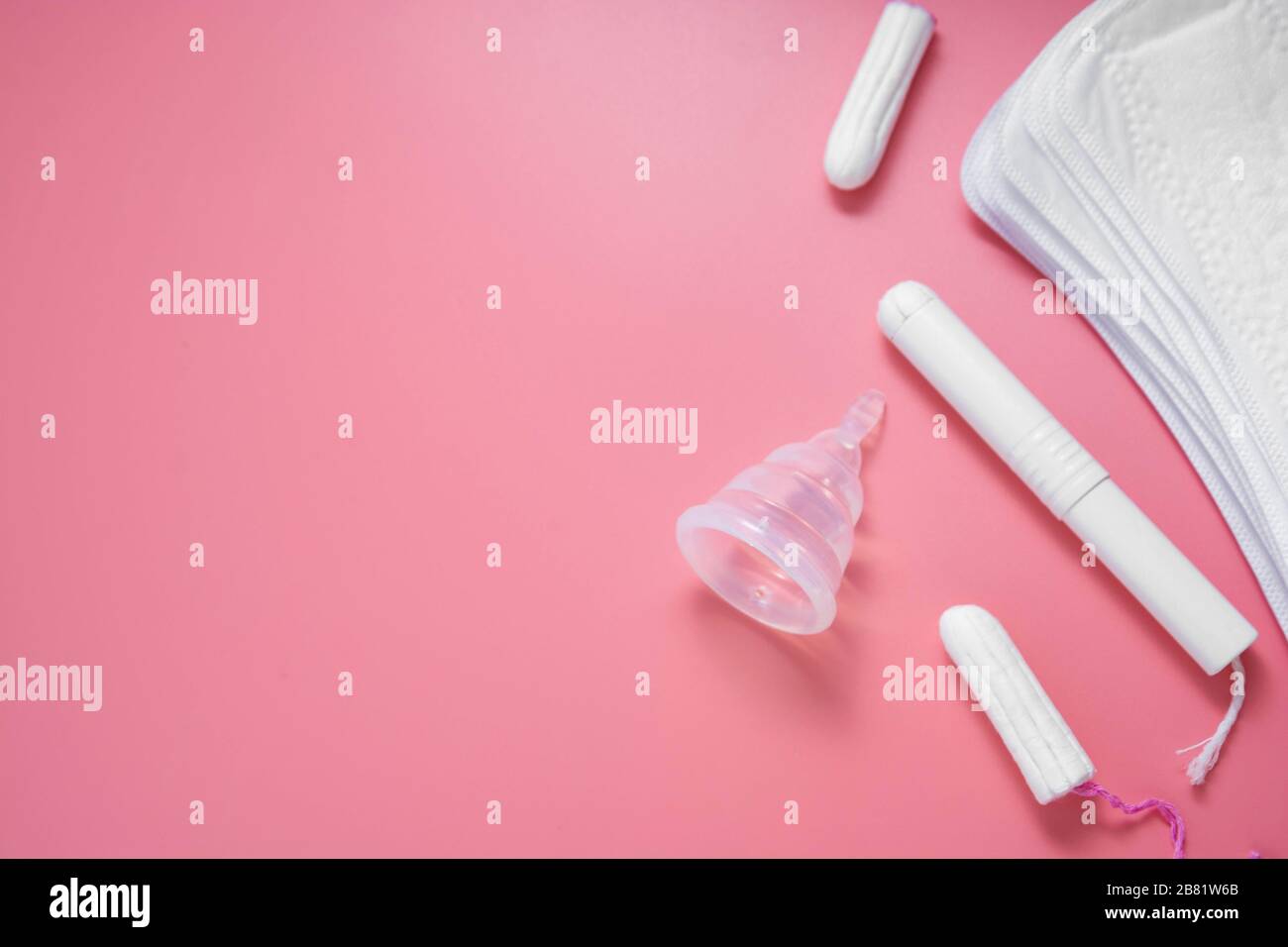 Hygieneprodukte für Frauen, Menstruation, Baumwolltampons, Sanitärpolster, Menstruationsbecher für Frauen kritische Tage. Rosafarbener Hintergrund mit Kopierbereich. Stockfoto