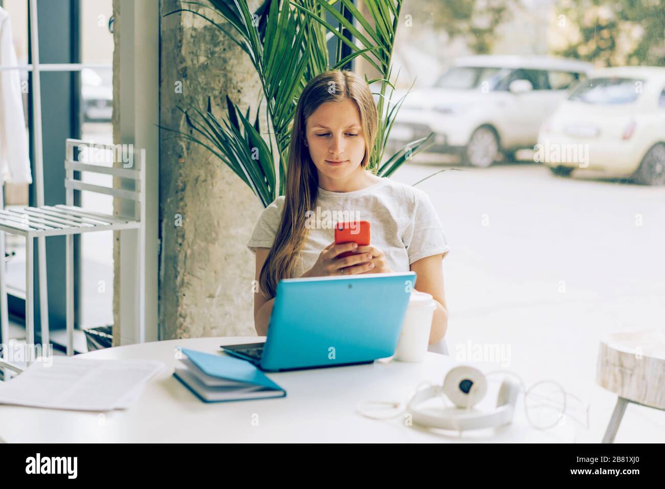 Eine junge weibliche Person durchstöbere am Telefon und am Laptop am frühen Morgen soziale Nachrichten. Stockfoto