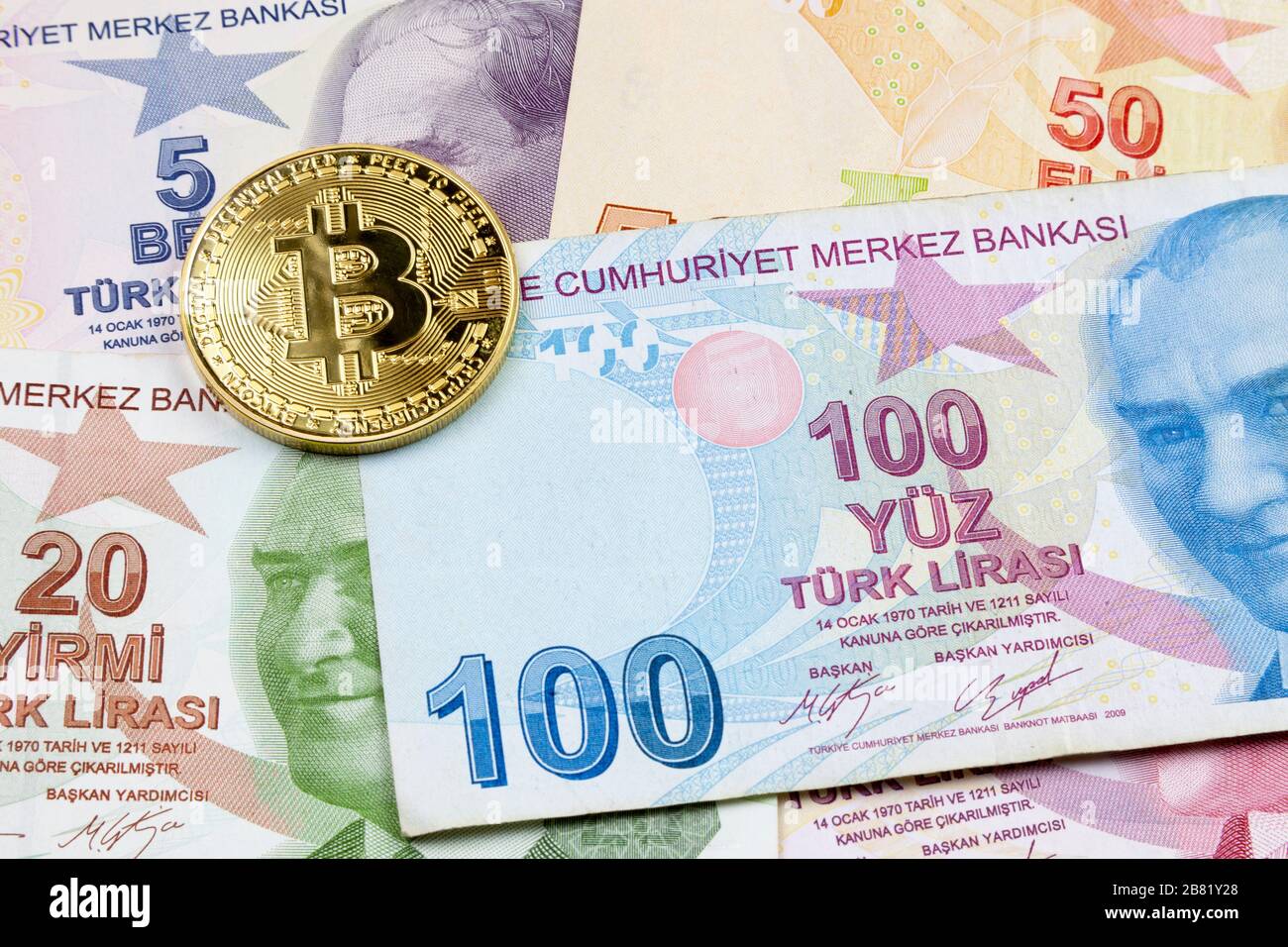 Nahaufnahme einer goldenen Bitcoin-Münze auf einem Stapel türkischer Lira-Banknoten. Stockfoto