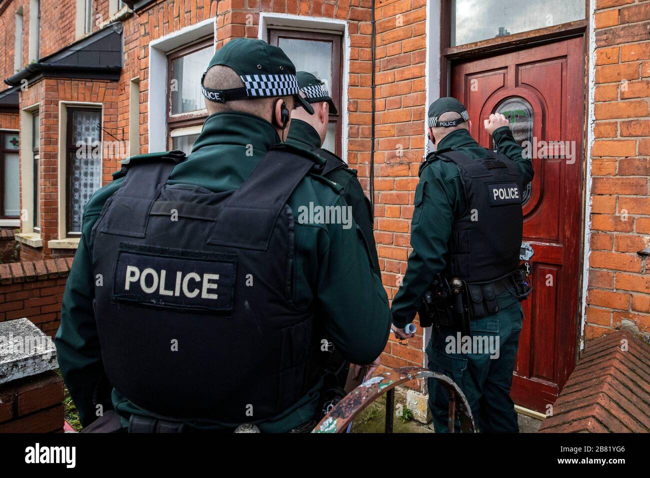 PSNI TSG-Beamte betreten bei einer Suche in einer terrassenförmigen Straße abseits der Crumlin Road im Shankill Gebiet im Norden von Belfast ein Anwesen. Die Suche war Teil der Operation Pangea, die den Online-Verkauf von gefälschten und illegalen Medikamenten und Medizinprodukten zum Ziel hat. Stockfoto