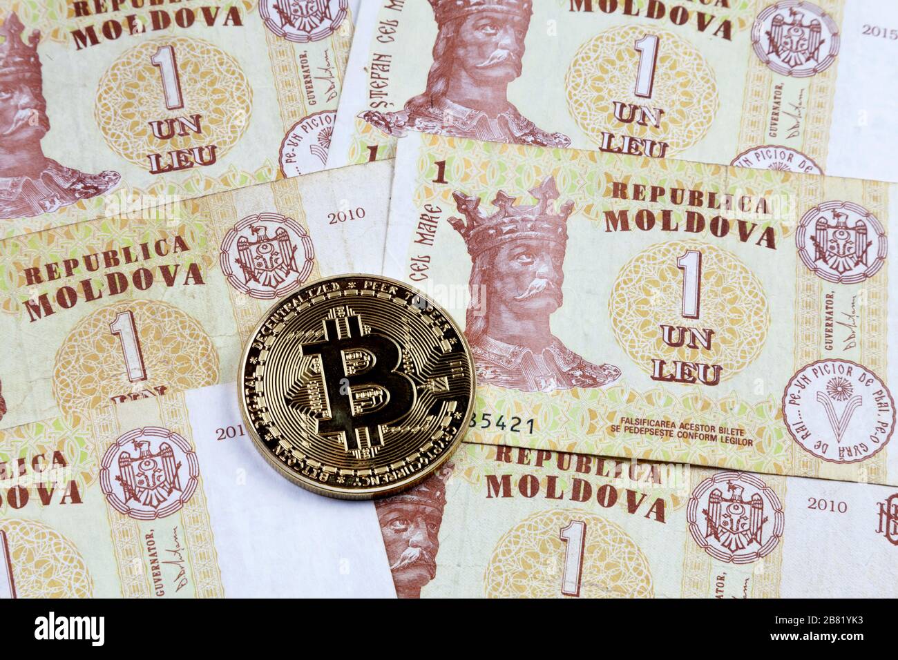 Nahaufnahme einer goldenen Bitcoin-Münze auf einem Stapel von moldauischen leu-banknoten. Stockfoto