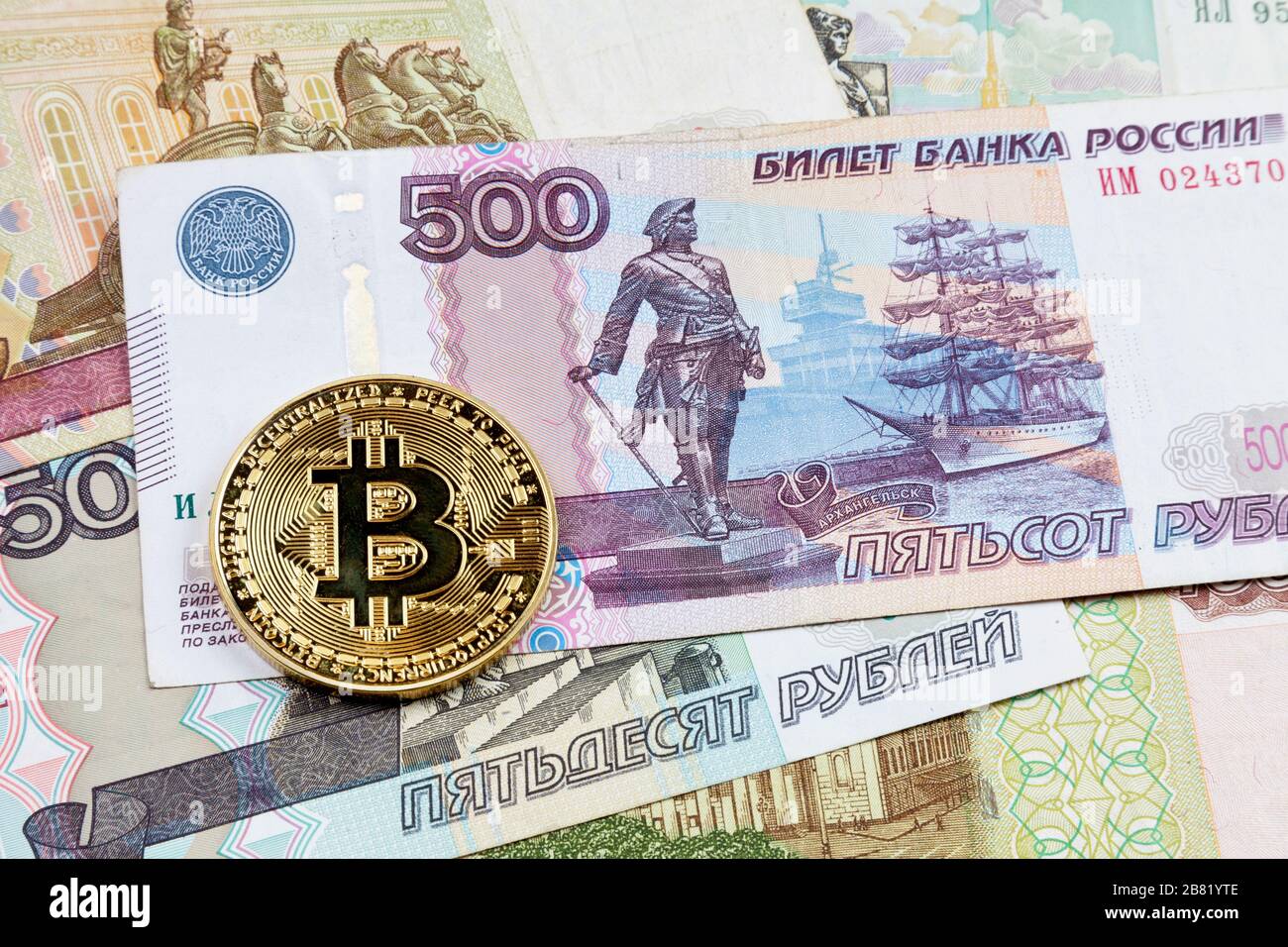 Nahaufnahme einer goldenen Bitcoin-Münze auf einem Stapel russischer Rubel-Banknoten. Stockfoto