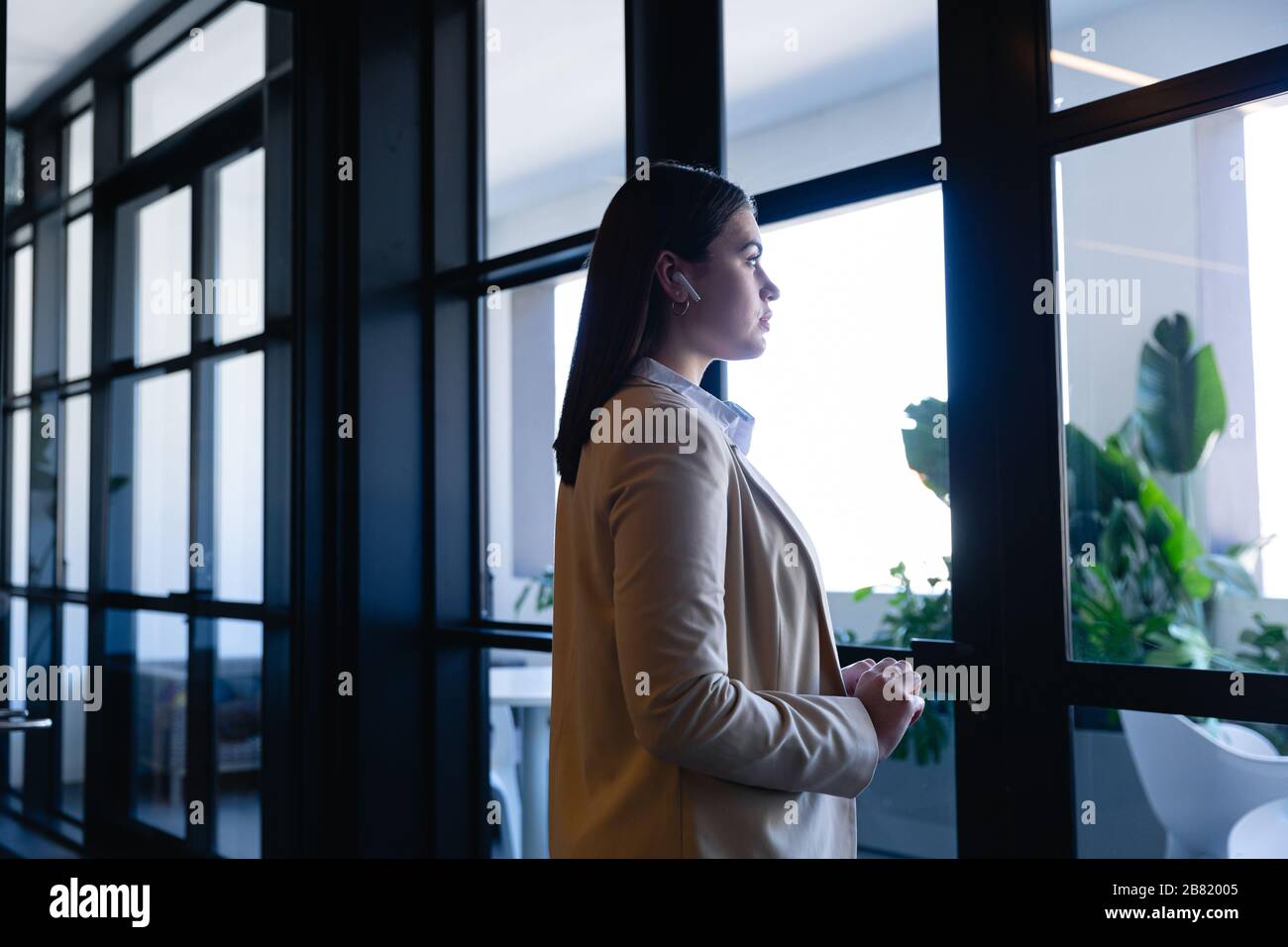 Kaukasische Frau, die nach draußen schaut und schnurlose Kopfhörer trägt Stockfoto