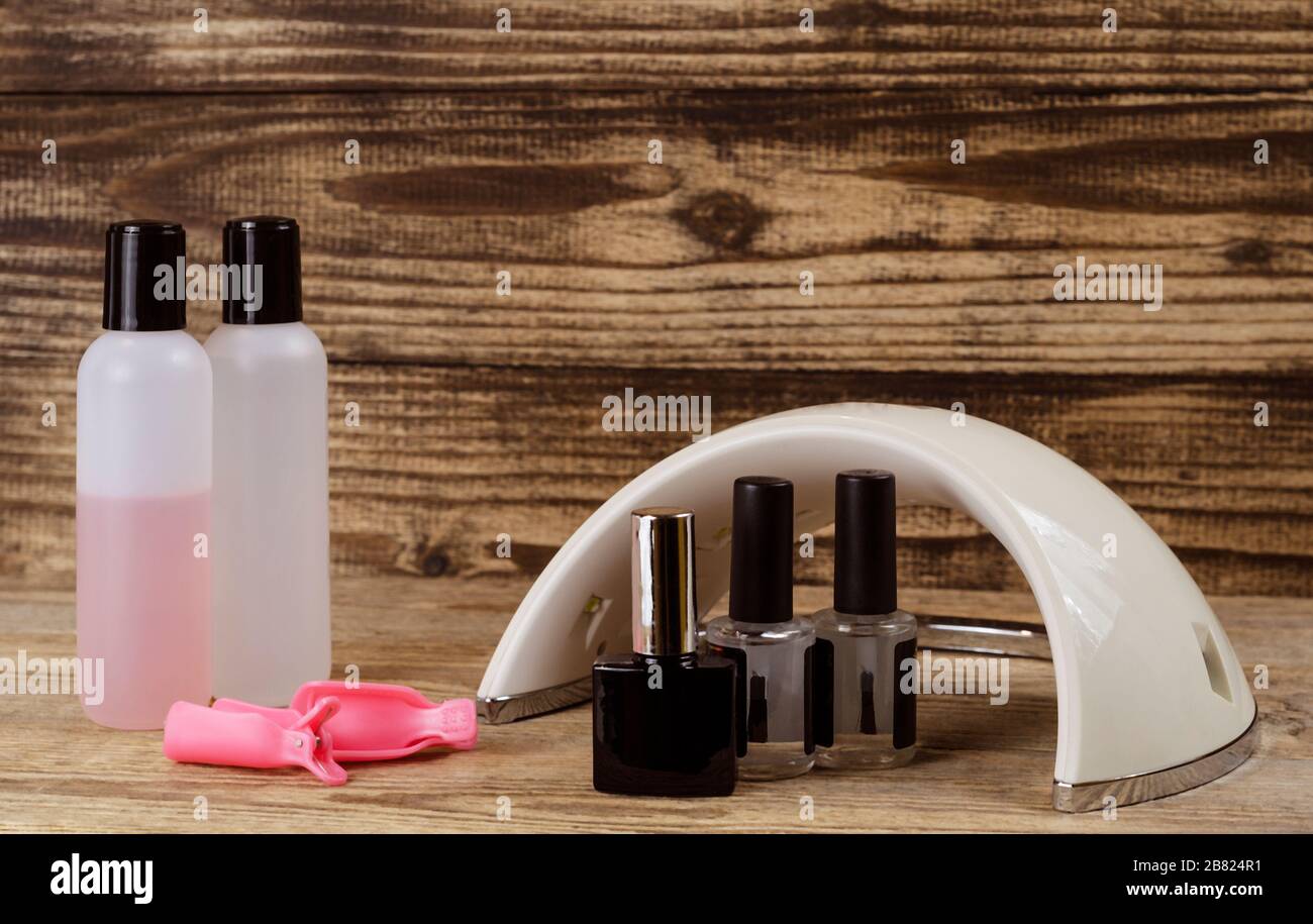 LED-Lampe und Zubehör für Nagelservice auf Holzhintergrund Stockfoto