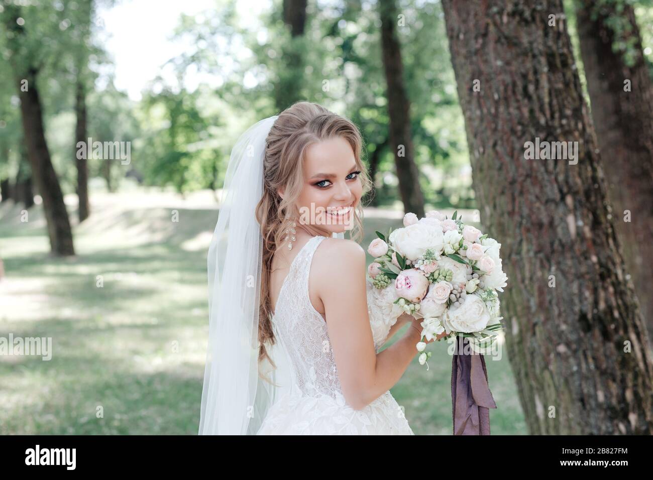 Schöne, im Park lächelnde Frau mit Blumenstrauß Stockfoto