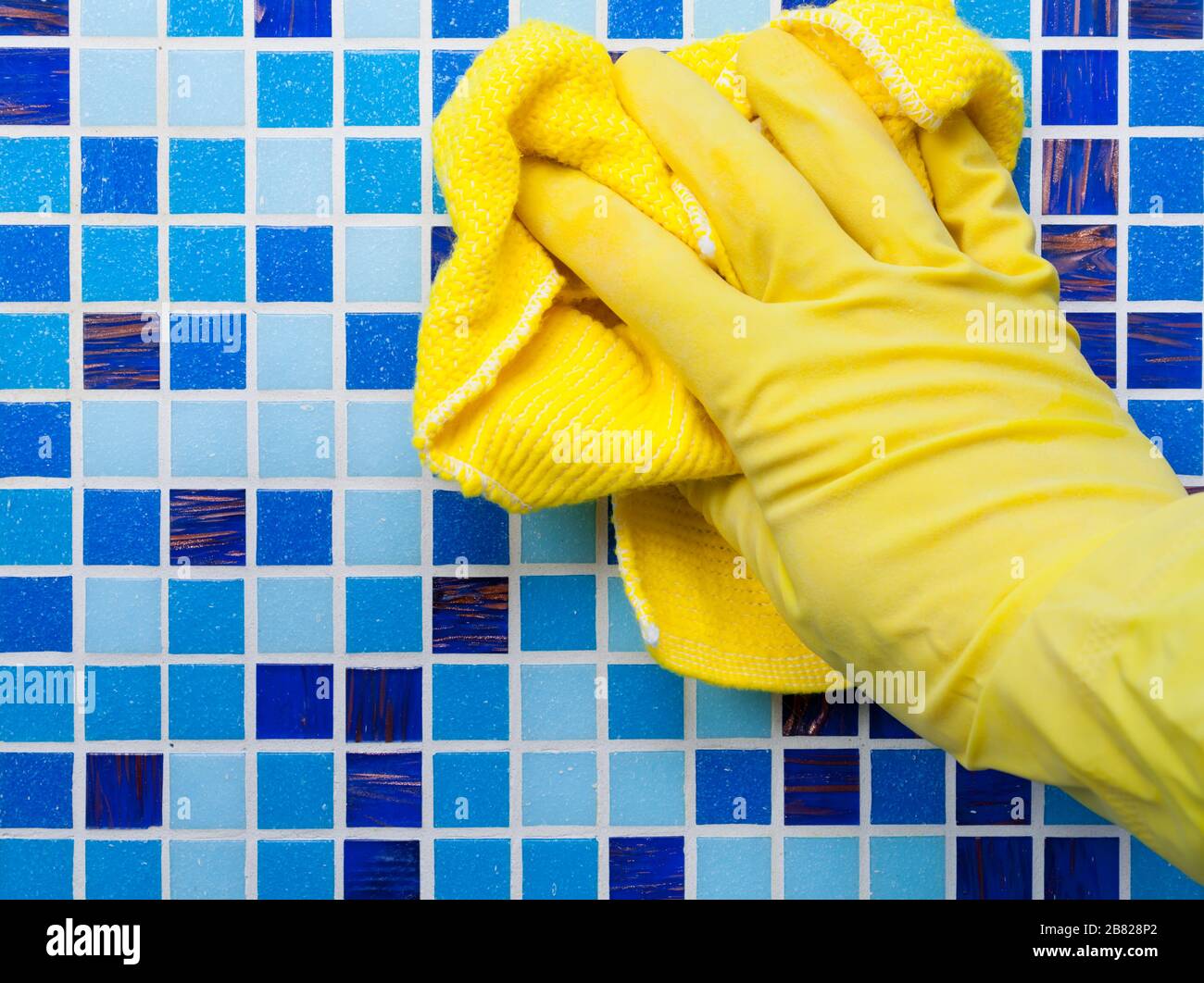 Person, die im Badezimmer zu Hause Arbeit verrichten und die geflieste Wand mit Mikrofasertuch reinigen kann Stockfoto