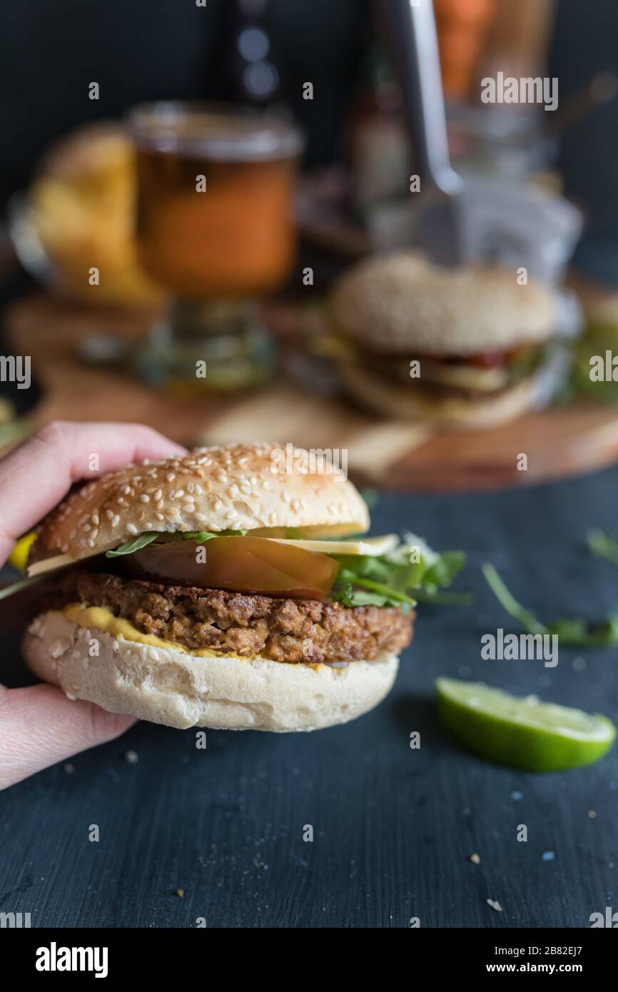 Köstlicher Closeup veggie quorn Burger. Hinten gibt es einen weiteren veganen Burger, einen Bierbecher, Pommes und mehr. Stockfoto