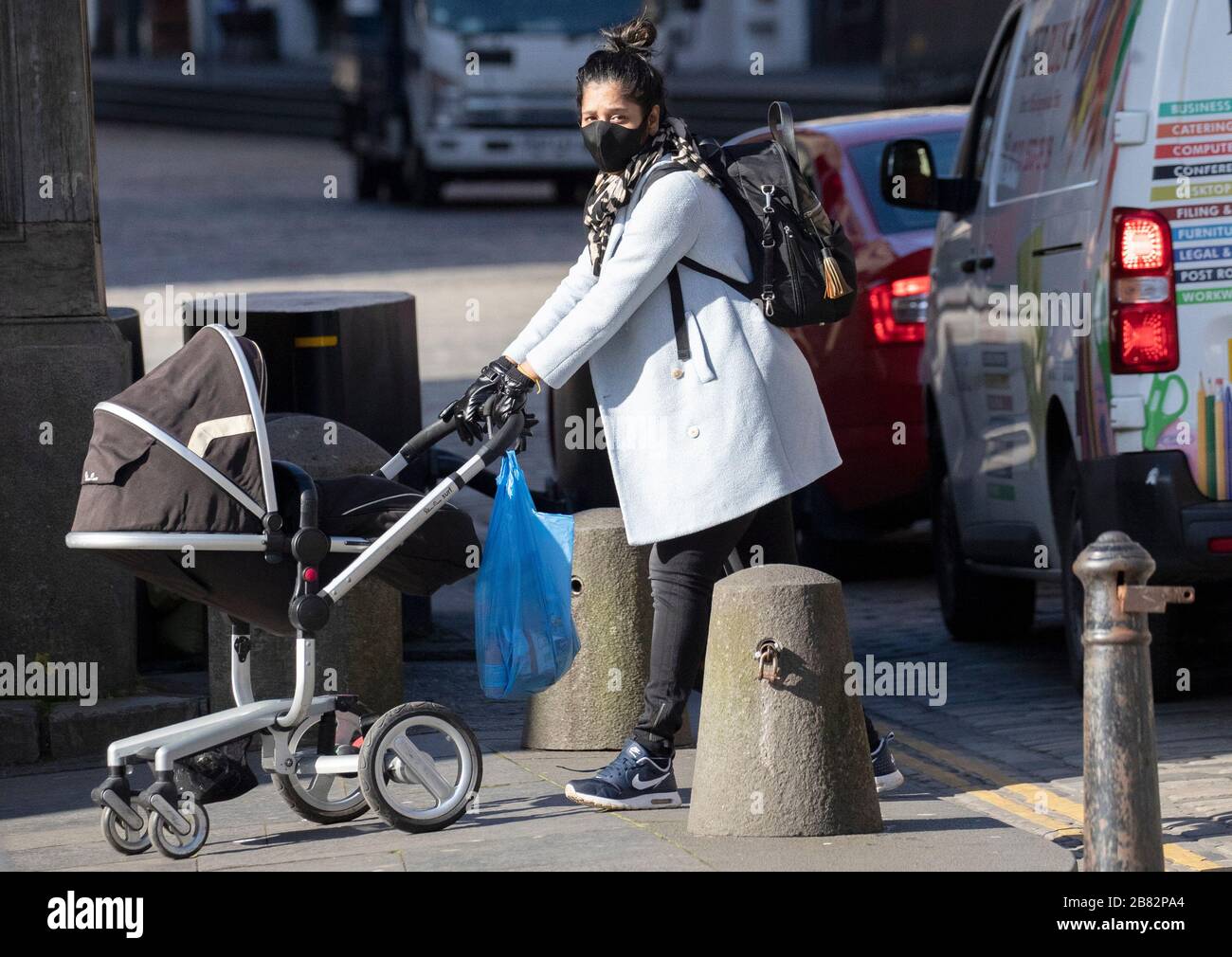 Eine Frau, die eine schützende Gesichtsmaske trägt, spaziert während des Ausbruchs des Coronavirus entlang der Royal Mile von Edinburgh. Stockfoto