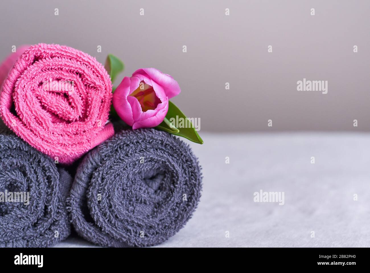 Ein Stapel frische Handtücher in Rollen mit pinkfarbener Blume, das Konzept der allgemeinen Ordnung und Sauberkeit und der Wäsche im Hotel Stockfoto