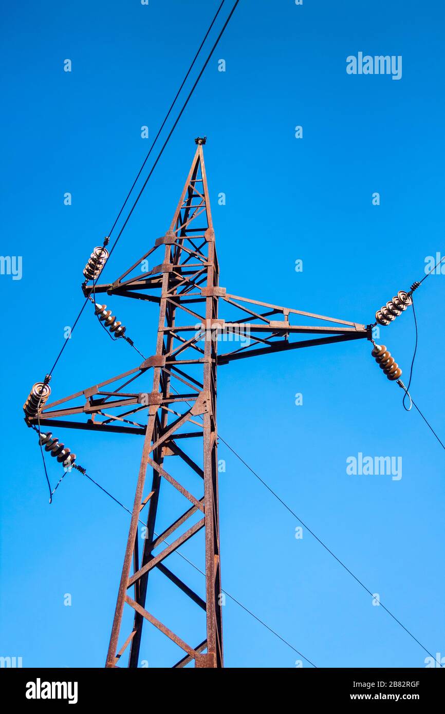 Alter rostiger Hochspannungspol vor blauem Himmel Hintergrund Stockfoto