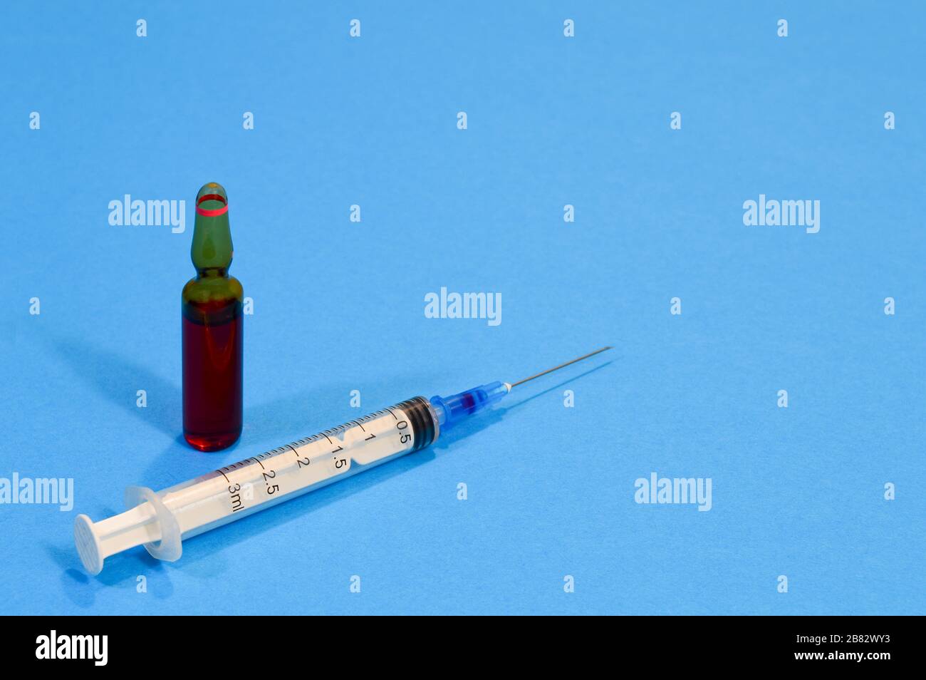 Ampulle mit Impfstoff aus einem neuen Coronavirus und einer Spritze auf blauem Hintergrund, Grippeimpfungskonzept Stockfoto
