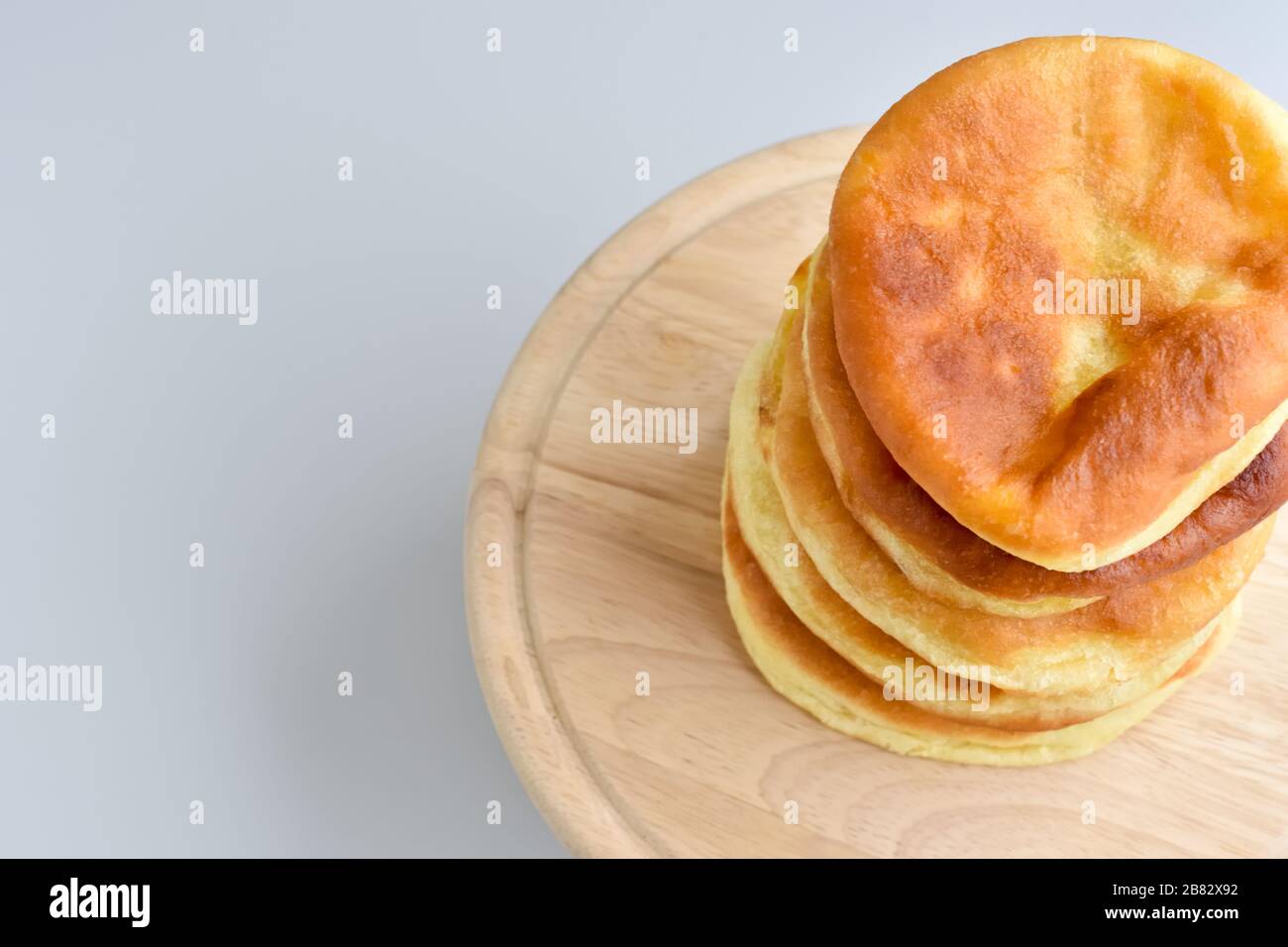 Gestapelte Pfannkuchen auf einer runden Holzschnittplatte mit Platz für Text. Blick von oben auf ein handgefertigtes Backwaren. Home gemütliches und komfortables Konzept Stockfoto