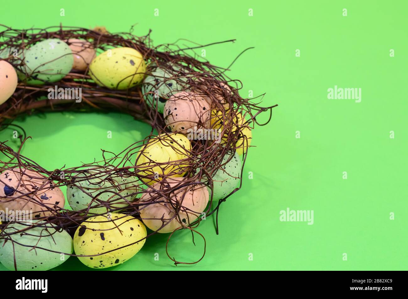 osterkranz mit bunten Eiern, handgefertigte festliche Innendekoration auf grünem Hintergrund, Kopierraum Stockfoto