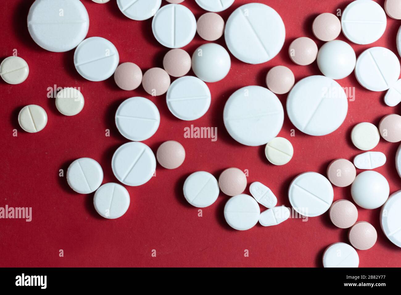 Haufen weißer Pillen, Tabletten, Kapseln auf rotem Hintergrund. Medikamentenverordnung für die Behandlung Medikation Gesundheitskonzept WTH-Kopierraum Stockfoto