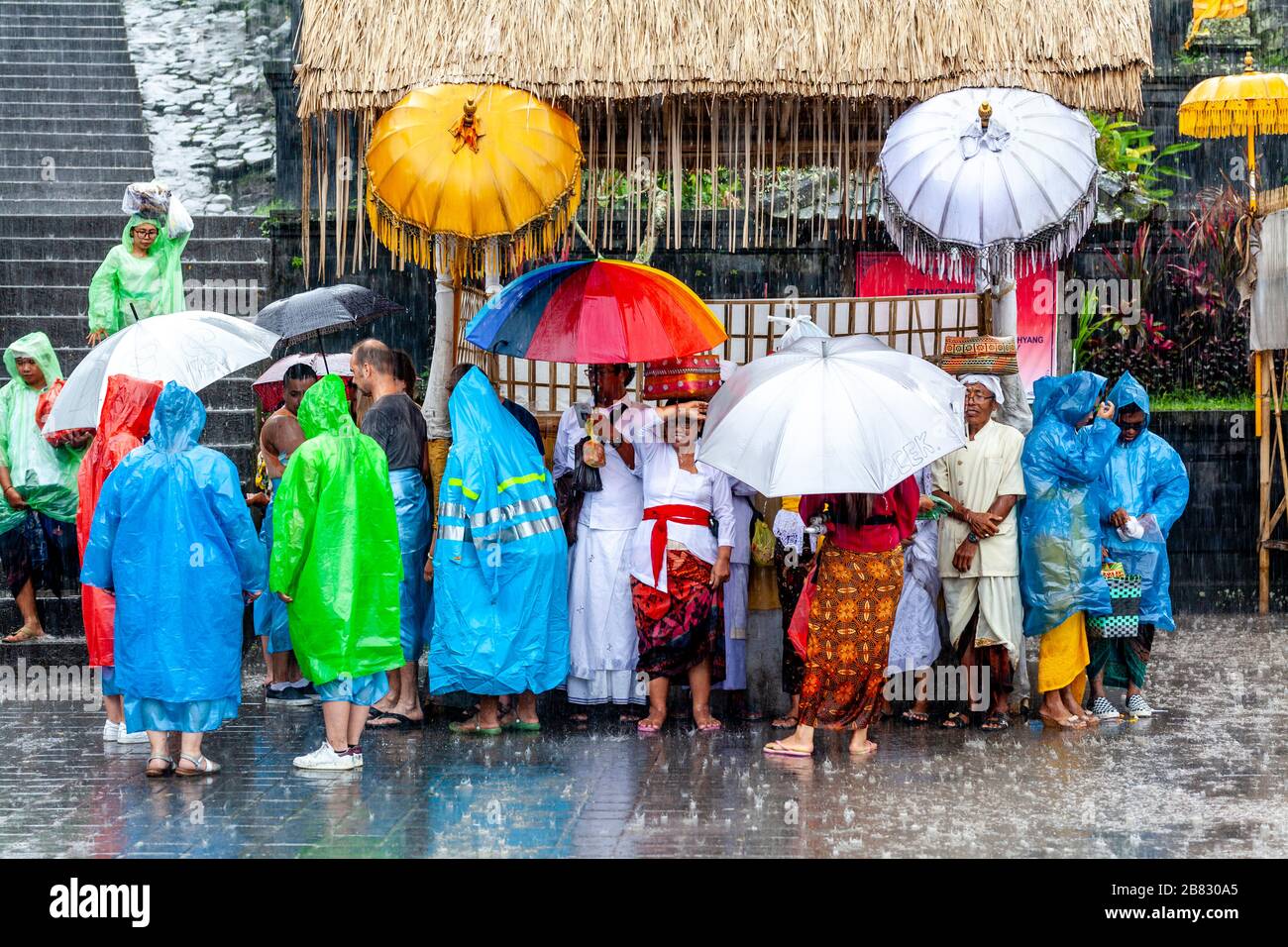 Besucher und Touristen schützen vor dem Regen bei der Zeremonie Batara Turun Kabeh, dem Besakih-Tempel, Bali, Indonesien. Stockfoto