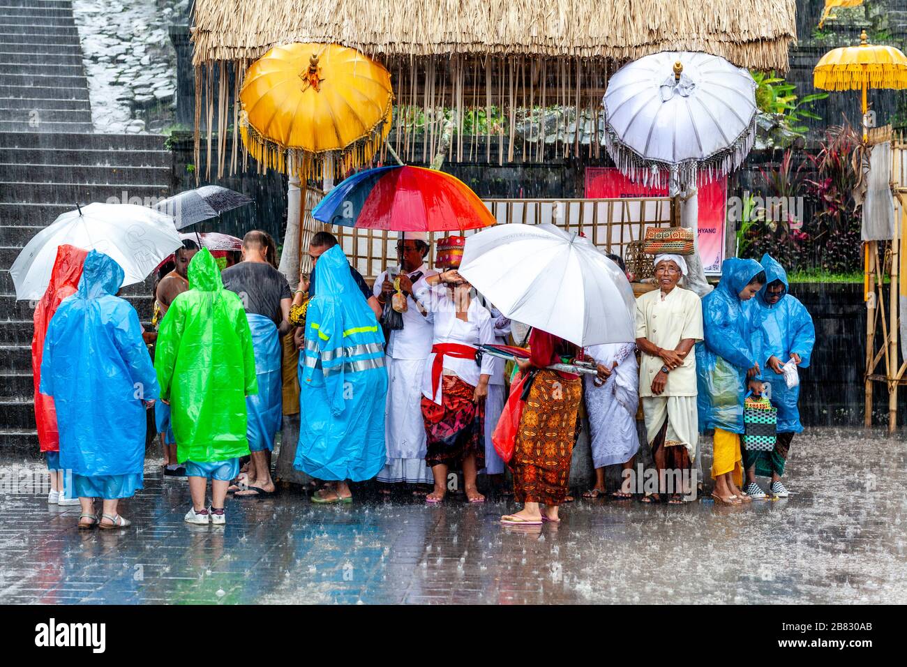 Besucher und Touristen schützen vor dem Regen bei der Zeremonie Batara Turun Kabeh, dem Besakih-Tempel, Bali, Indonesien. Stockfoto