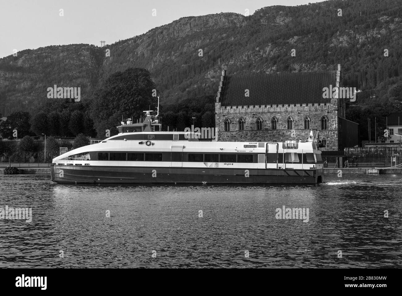 Schneller Passagierkatamaran Fjordbris, der vom Hafen von Bergen, Norwegen, abfährt. Vorbei an der alten Festung Haakonshallen Stockfoto