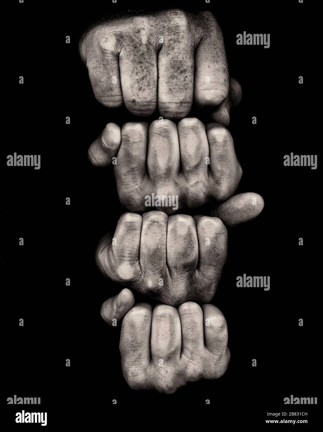 Vier gestapelte Fäuste vor schwarzem Hintergrund Stockfoto