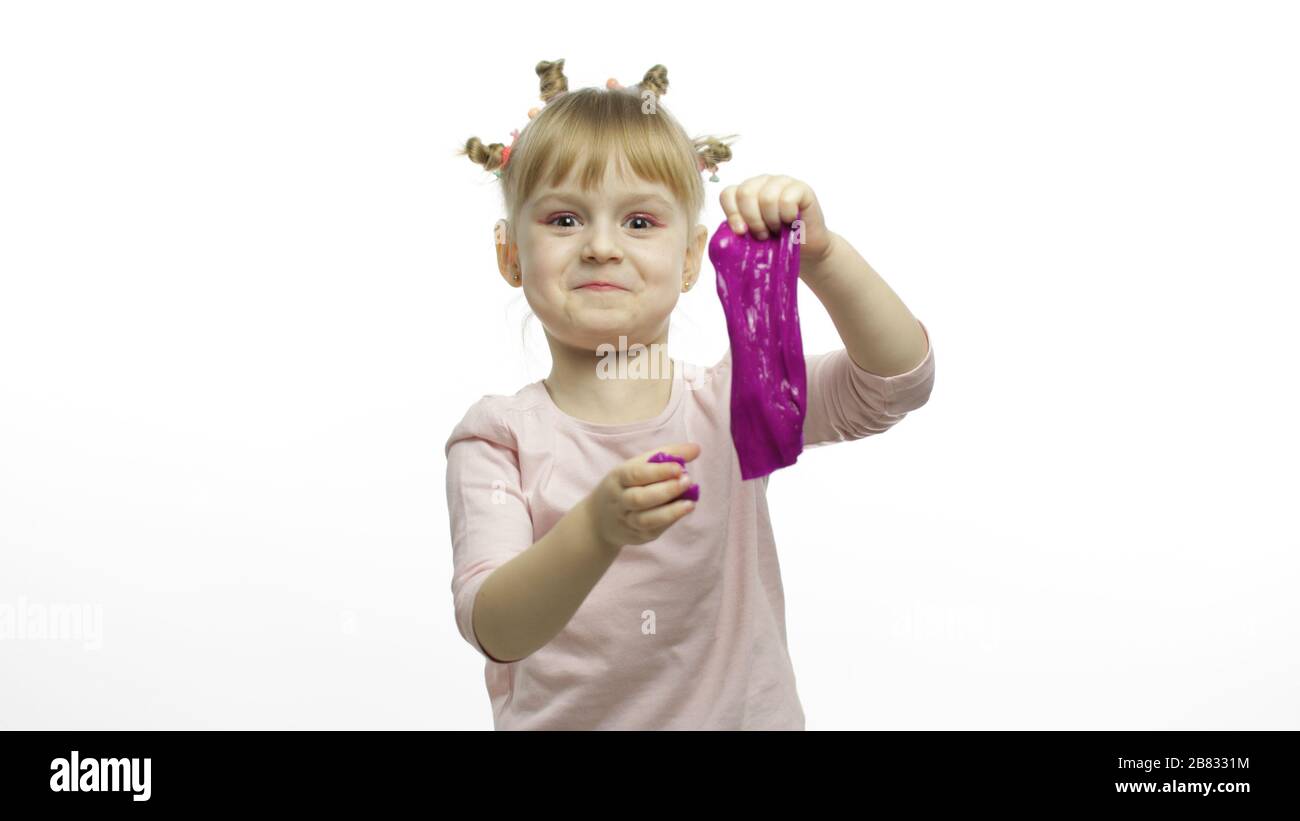 Kind hat Spaß, lila Slime zu machen. Kinder, die mit handgefertigten Spielzeug-Slimen spielen. Lustige Kid Girl. Entspannung und Zufriedenheit. Ungewöhnlich befriedigender roter Slime für reinen Spaß und Stresslinderung. Weißer Hintergrund Stockfoto