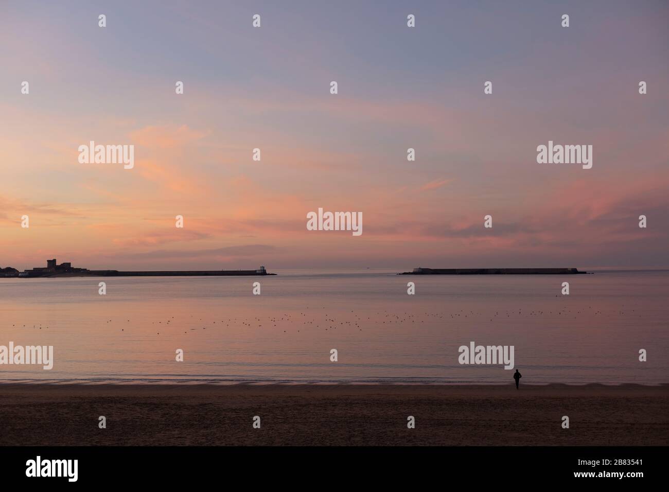 Der menschenleere Strand von Saint-Jean de Luz nach Sonnenuntergang, mit der Silhouette eines Mannes, der auf den Horizont blickt. Stockfoto