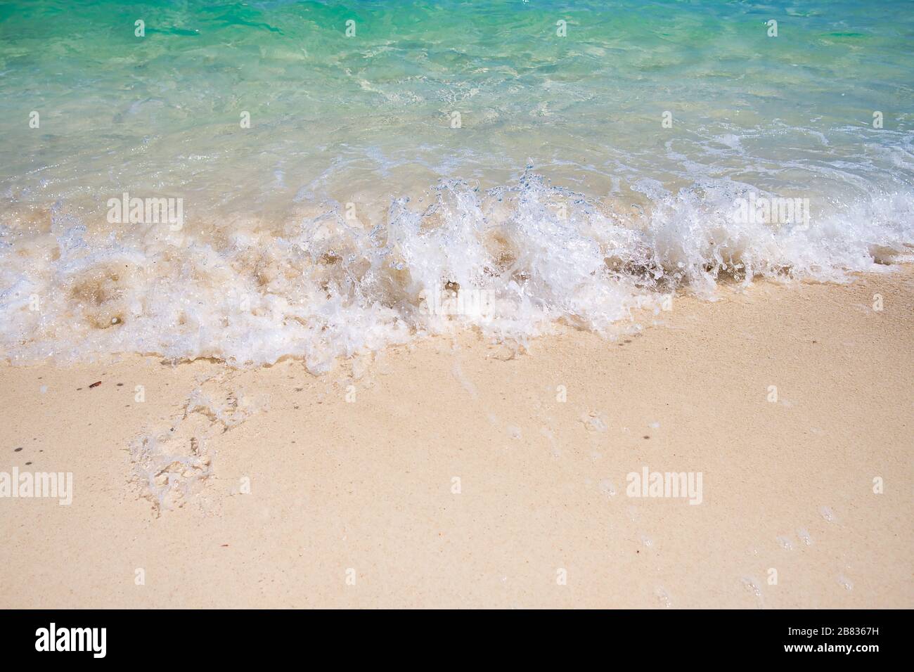 Sanftes blaues Meer am sauberen Sandstrand. Die blaue Meeresweiche Welle auf dem Sand berührt kontinuierlich und schön das Ufer Stockfoto